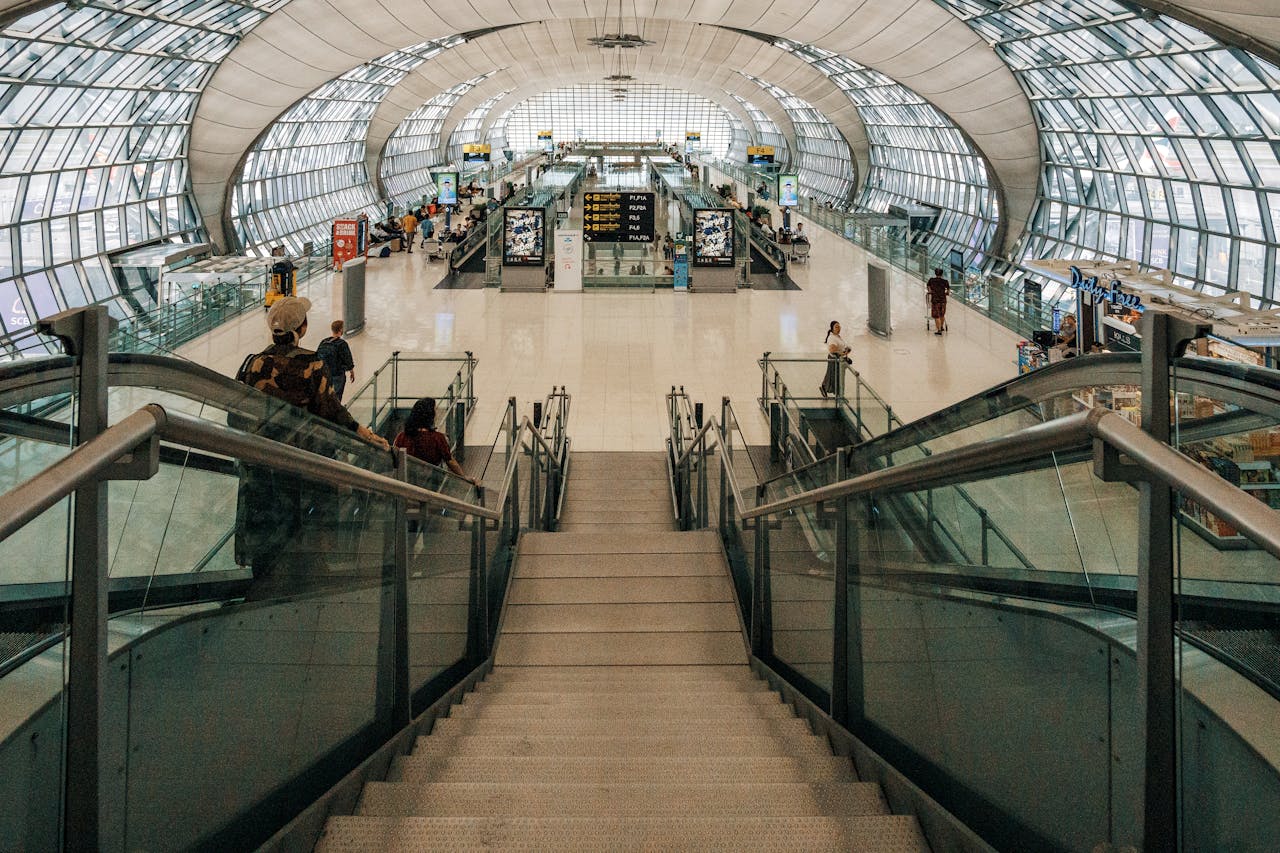 Spacious modern airport terminal featuring a glass dome design and descending stairway view.